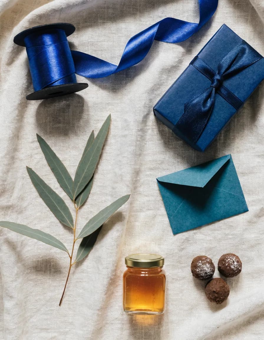 Gift-wrapping essentials: blue ribbon, navy box, honey and chocolate on linen